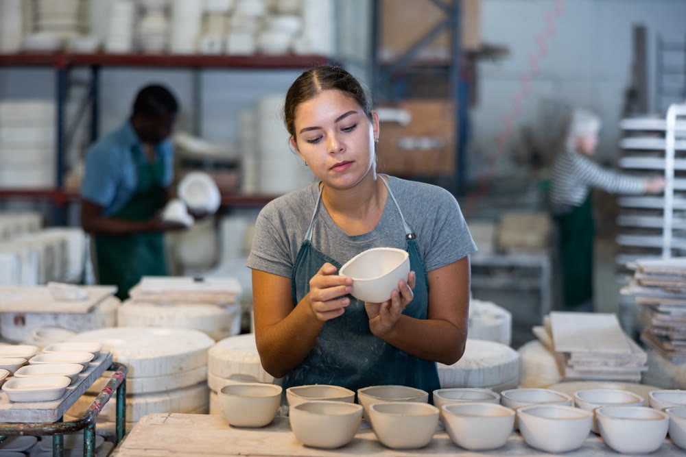 Young woman checks quality of pottery after being removed from plaster mold