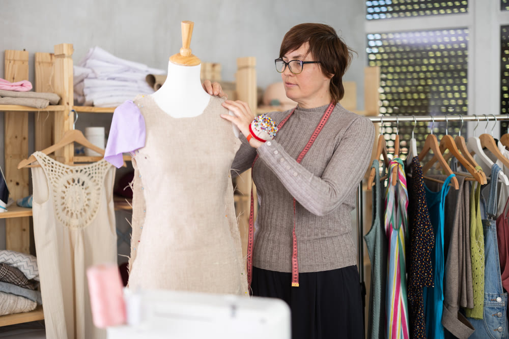 Female dressmaker trying on a new dress on a mannequin in sewing workshop