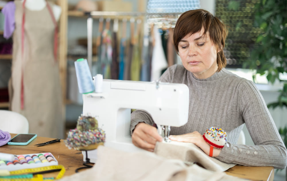Female seamstress working on sewing machine in workshop