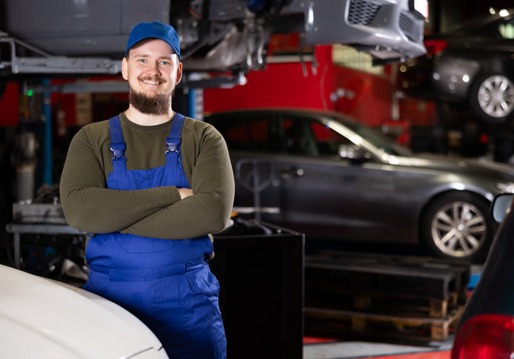 Young guy mechanic posing at car service station