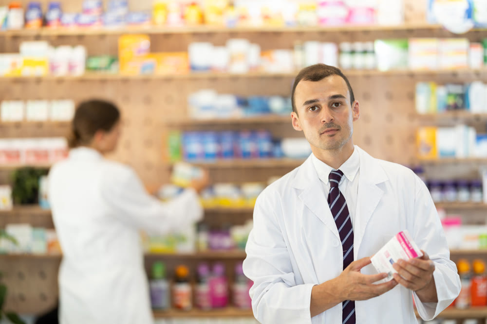 Young male pharmacist offering preparation in box