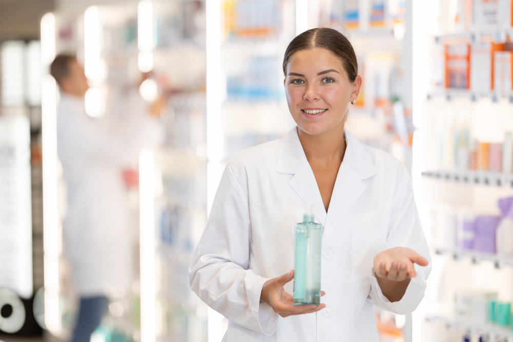 Girl pharmacist holds out bottle cosmetic