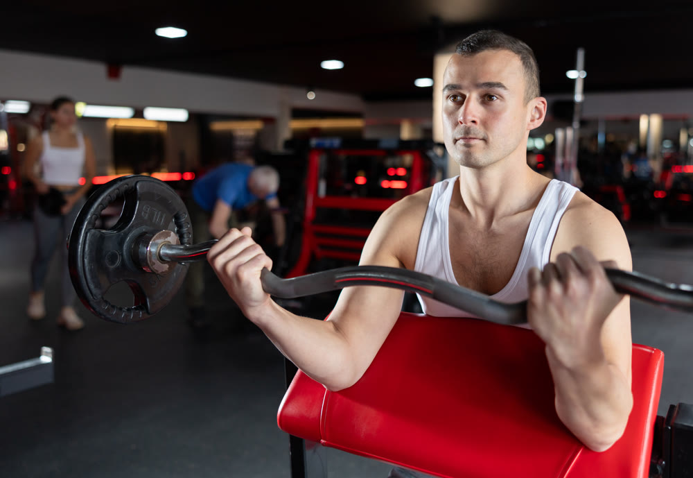 Young man training with barbell in gym