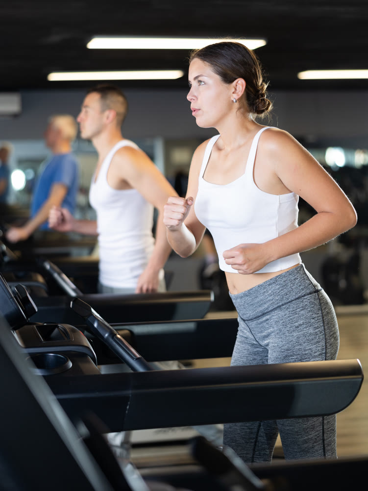 Young woman exercising on treadmill in gym