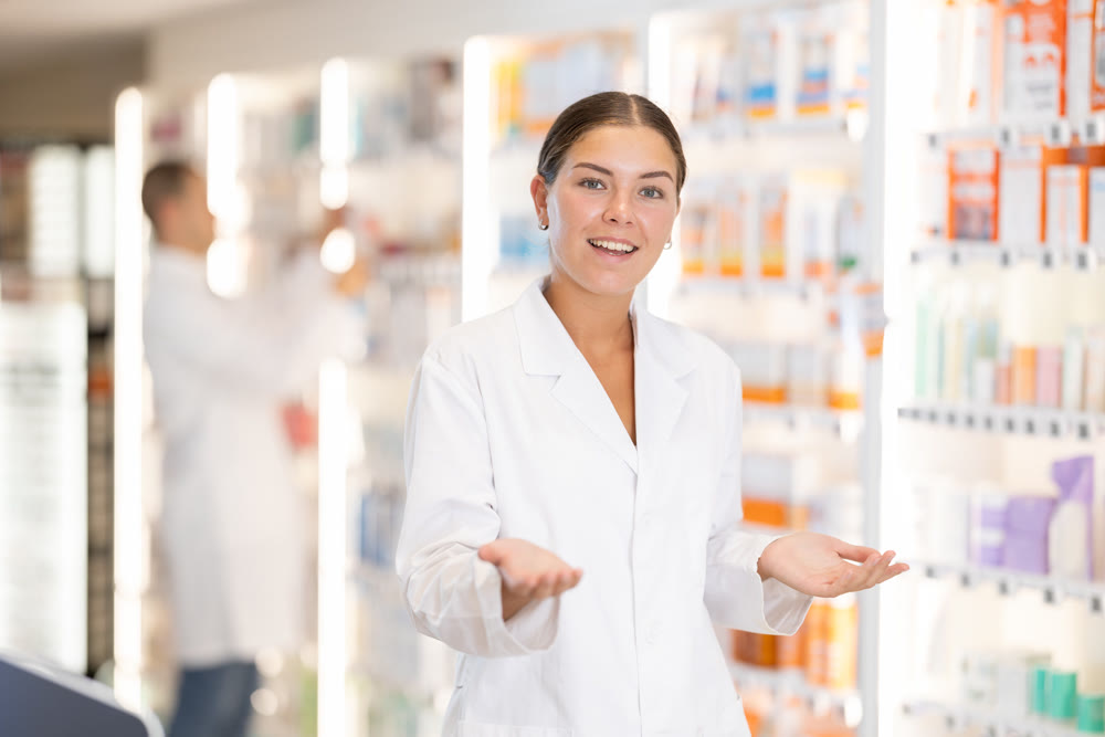 At pharmacy, girl apothecary waiting for customers, invite with gesture go to department of cosmetic