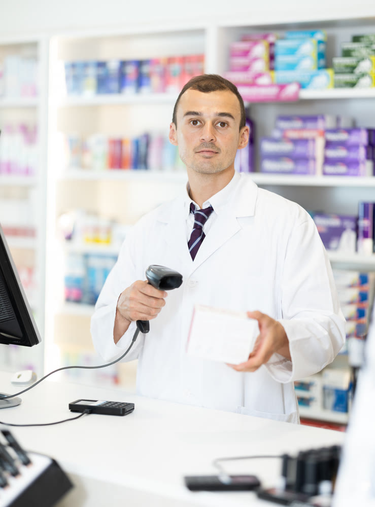Young male pharmacist scanning barcode on sold medicine box