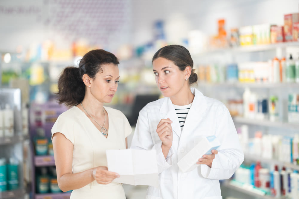 Female pharmacist giving prescription medicine to adult woman