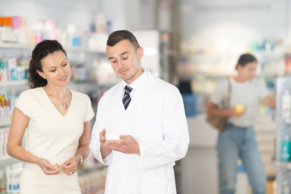Man pharmacist helps woman buyer to decide on choice an medicine