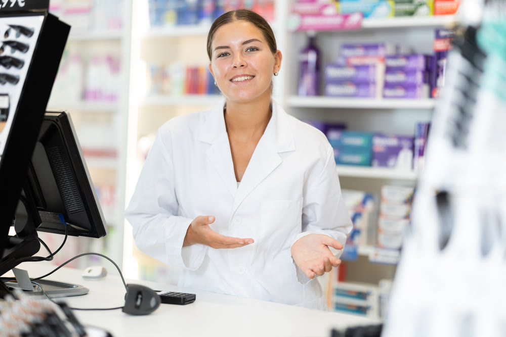Young female pharmacist welcoming clients in chemist's shop
