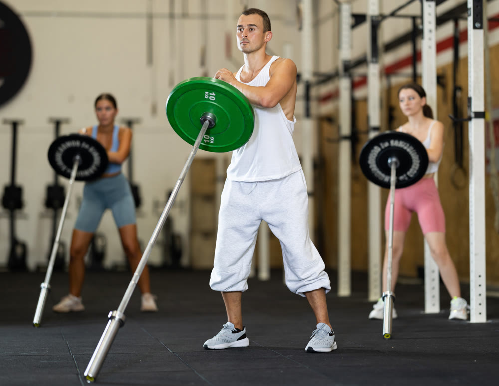 Athletic man pumping up her arm biceps using one side of barbell