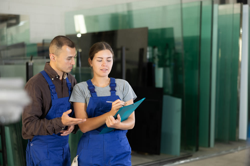 Two glass workshop workers discussing documents
