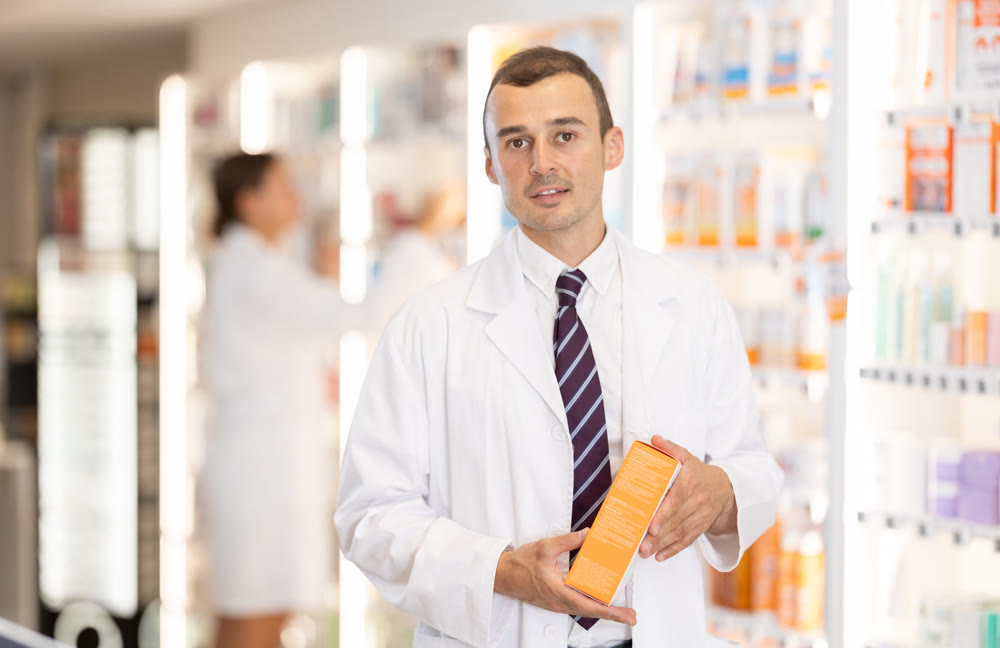 Young male pharmacist offering preparation in box