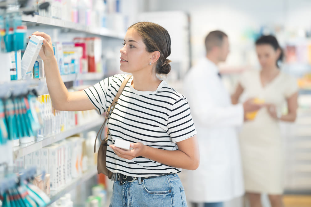 Young woman choosing medicine at pharmacy