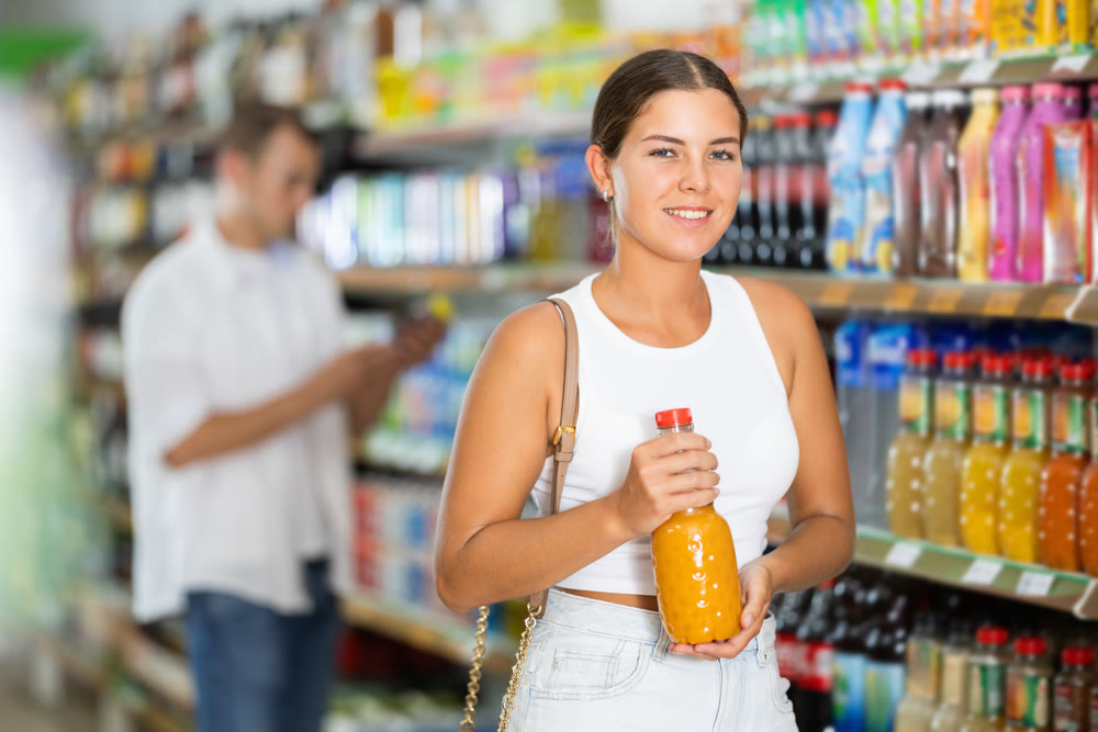 Young woman choosing soda in store