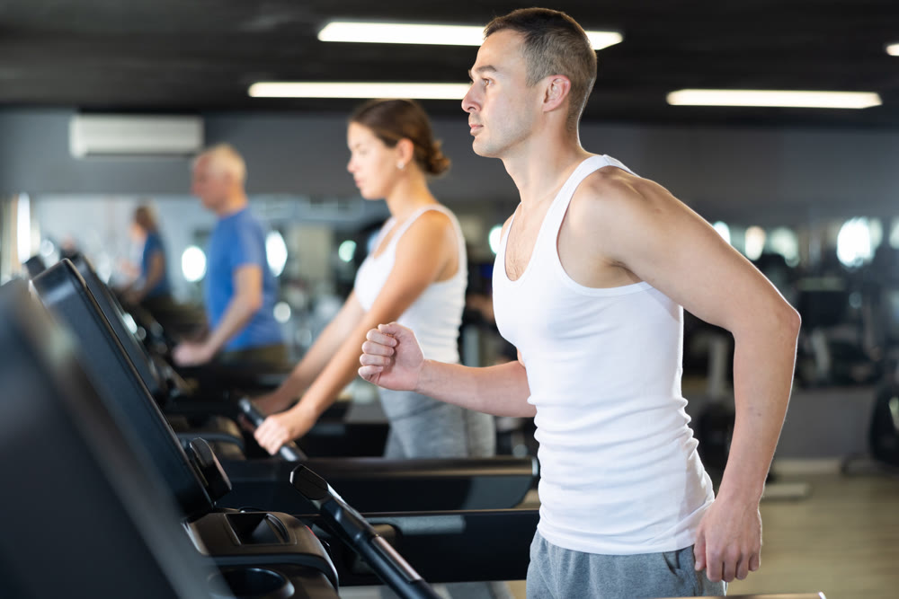 Young man exercising on treadmill in gym