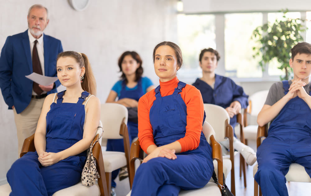 Young students in blue overalls attending technical seminar