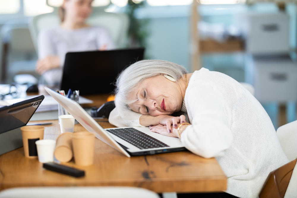 Tired women sleeps next to computer at work.