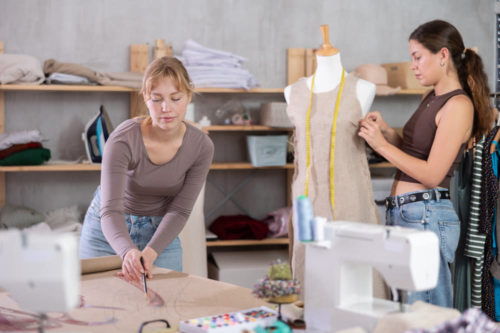 Women tailors design clothes and draw on paper in the workshop