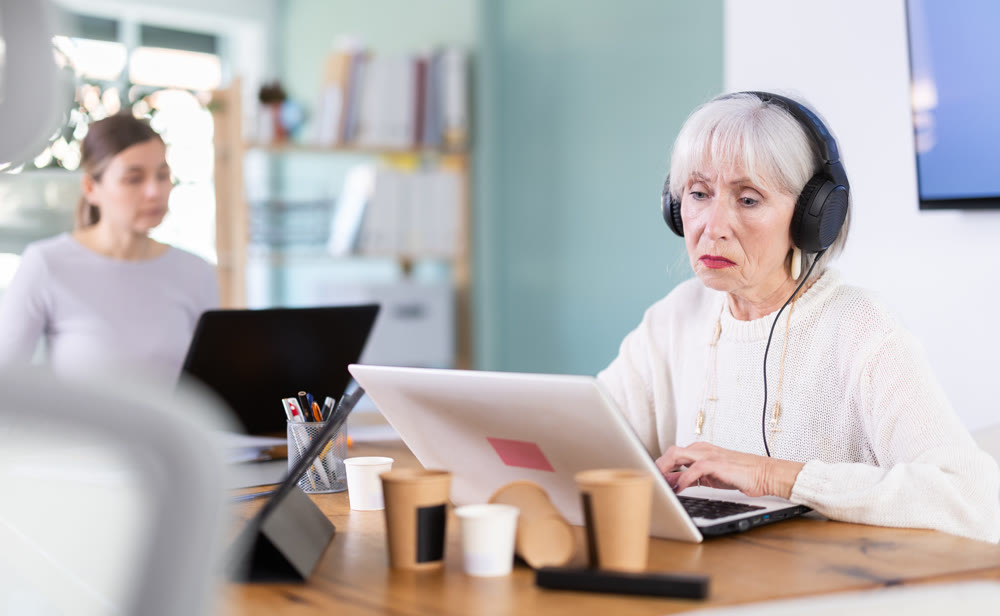 Two businesswomen work on laptops in modern company office