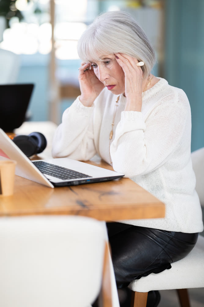 Elderly businesswoman suffers from headaches while working in office