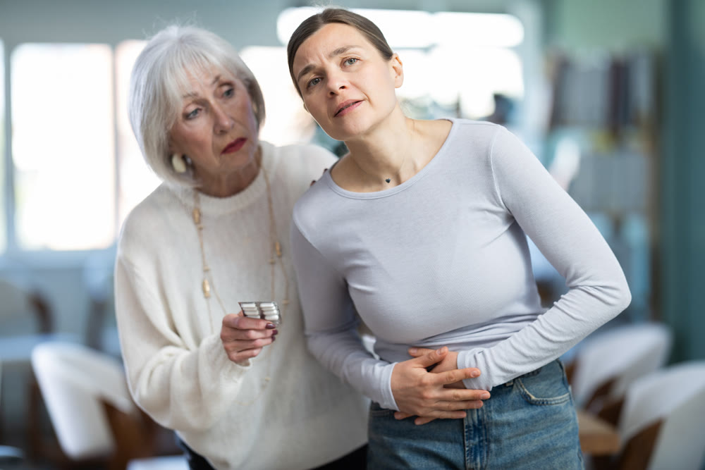 Adult woman with stomach pain, colleague gives painkillers