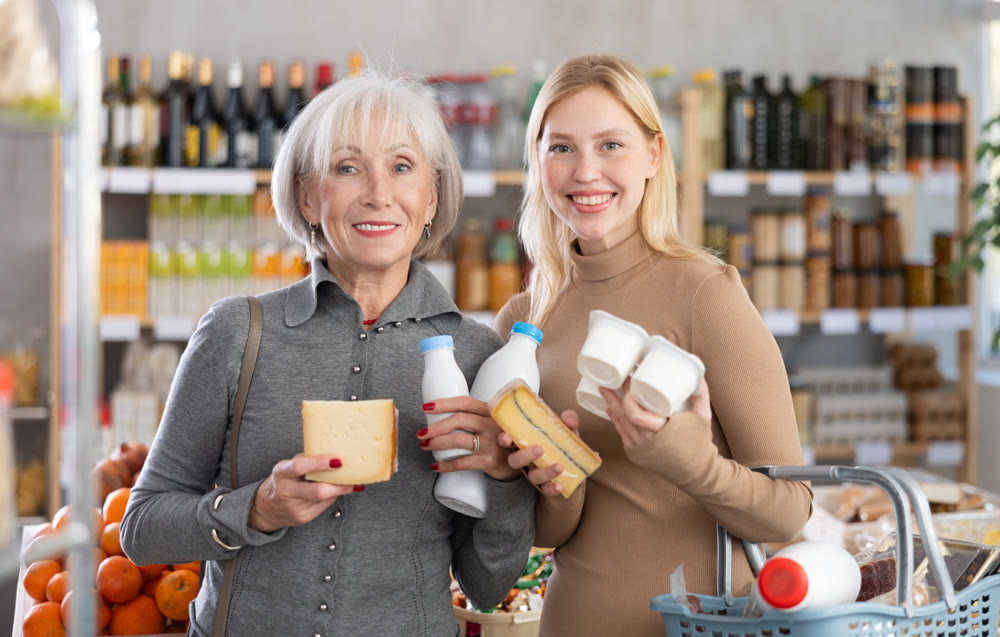 Girl and grandma with dairy products chooses something else, examines labels of cheese and yogurt