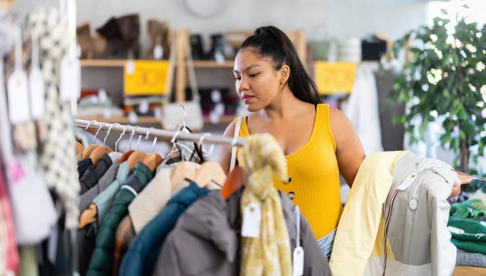 Young woman choosing down jacket in clothing store