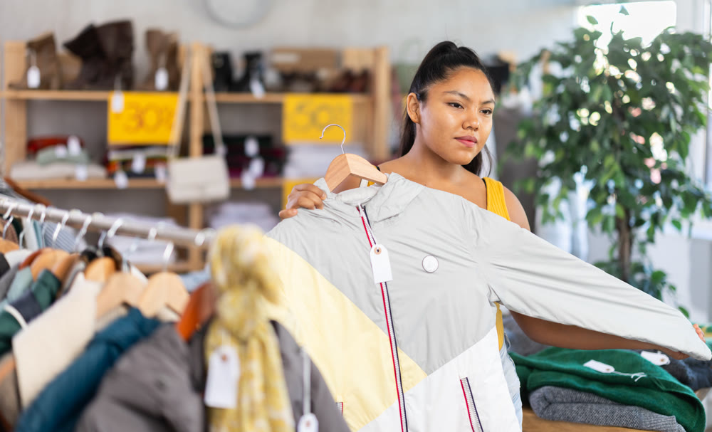 Woman chooses coat for the winter period in fashionable clothing store