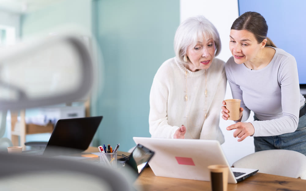 Two businesswomen drink coffee and discuss news during a break in office. Coffee break