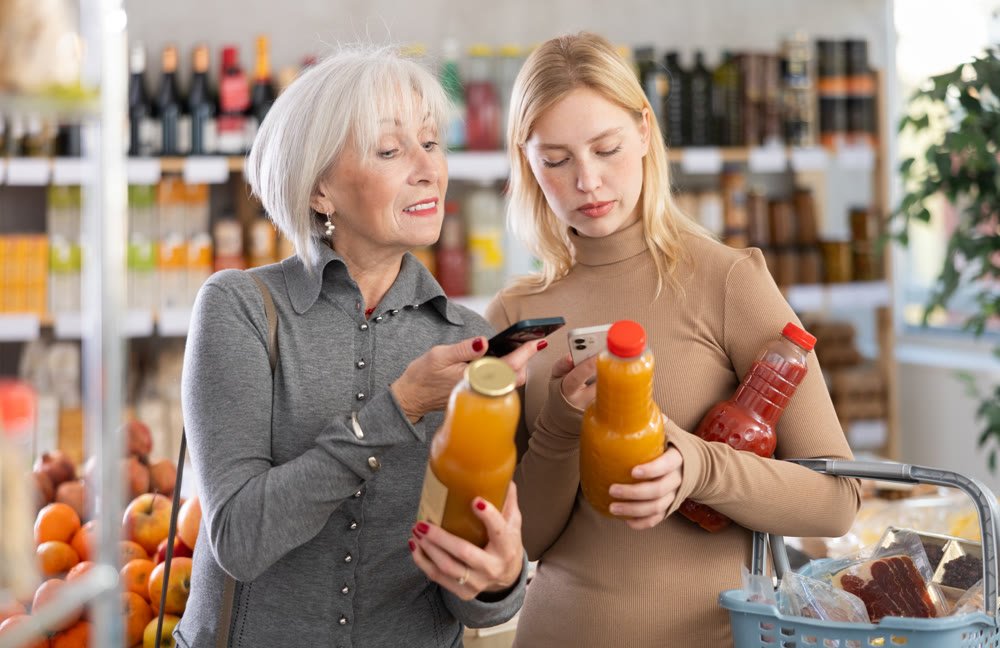 Girl and grandma scan QR code, take reading juice label using phone camera in shop