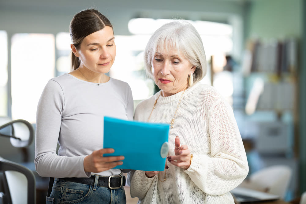 Woman shows elderly colleague documents
