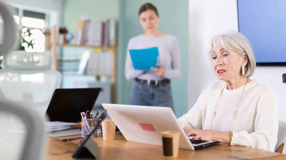 Elderly businesswoman, senior manager, work on laptop in modern company office