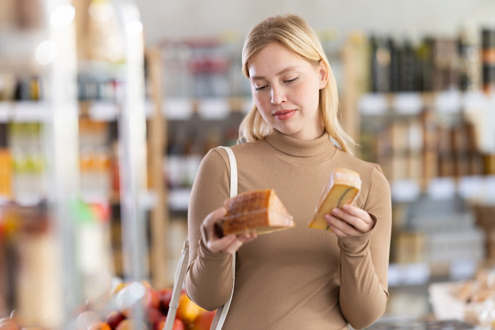 Girl buyers examine good, doubt and choose cheese in store