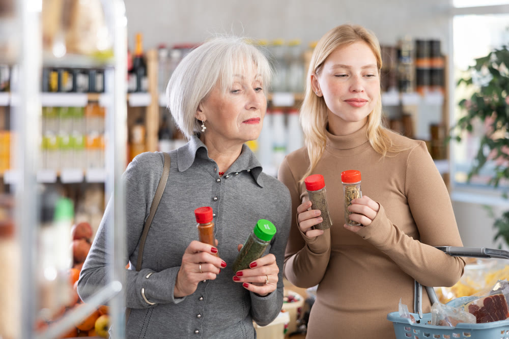 Elderly mother with her adult daughter chooses spices and seasonings to buy in grocery department section of store