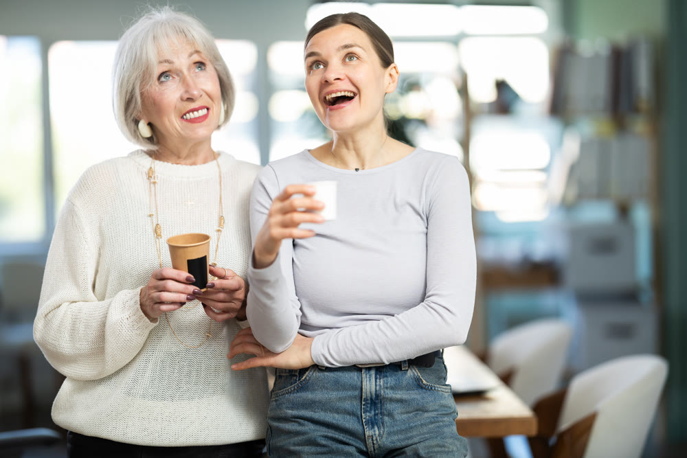 Two businesswomen drink coffee and discuss news during a break in office. Coffee break