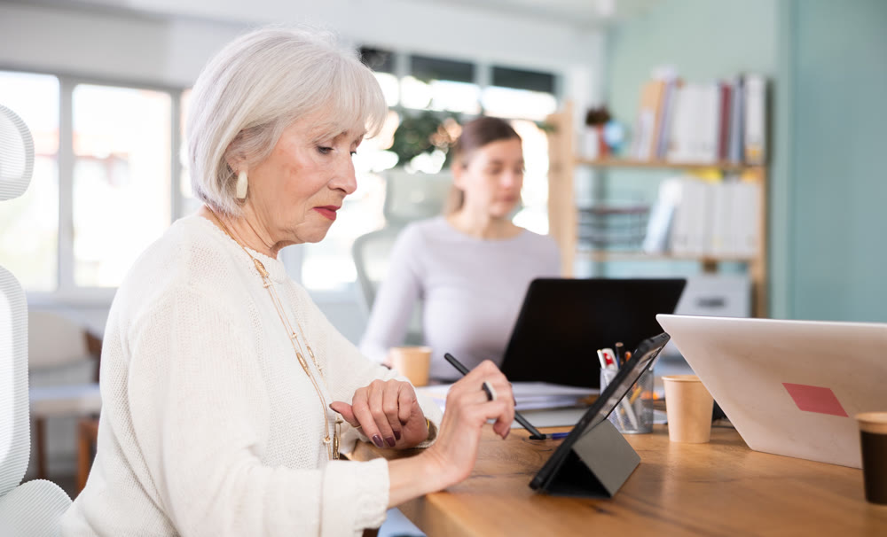 Two businesswomen work on laptops in modern company office