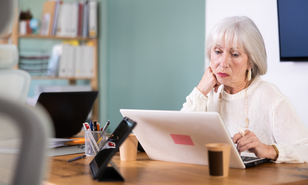 Senior woman working in office, using laptopat workplace.