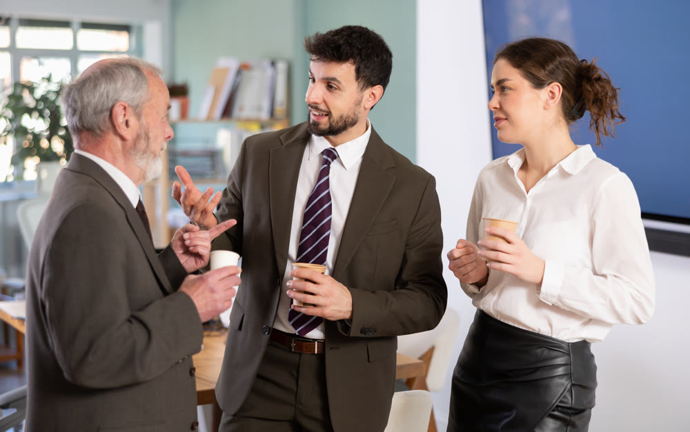 Girl with two men colleagues chat and laugh during coffee break
