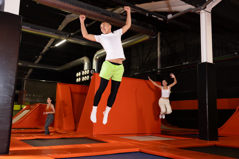 Emotional man jumping vertical and flying in trampoline sport center indoors
