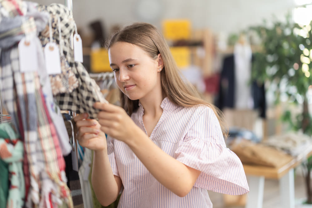Teenage girl choosing some scarf in clothing store