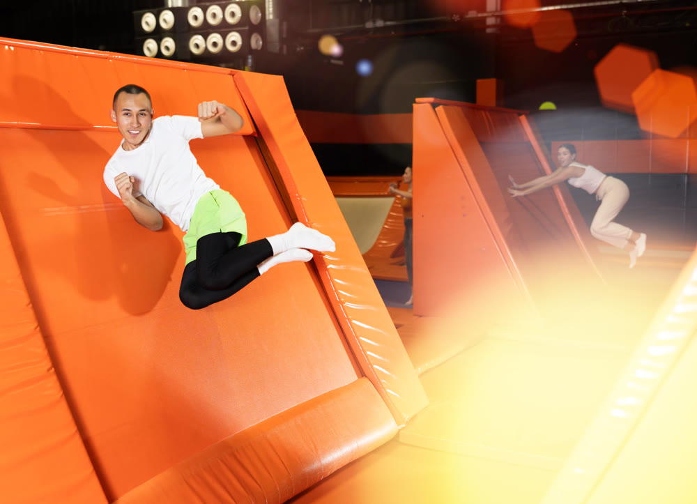 Excited man pushing off from inclined surface in indoor trampoline center