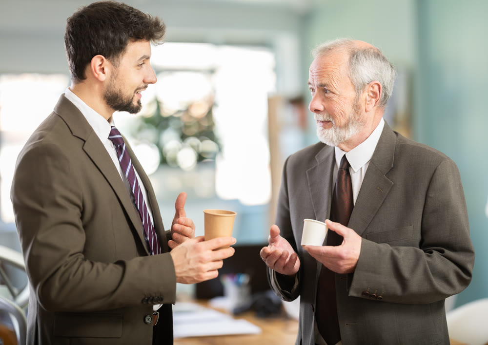 Two men colleagues chat and laugh during coffee break