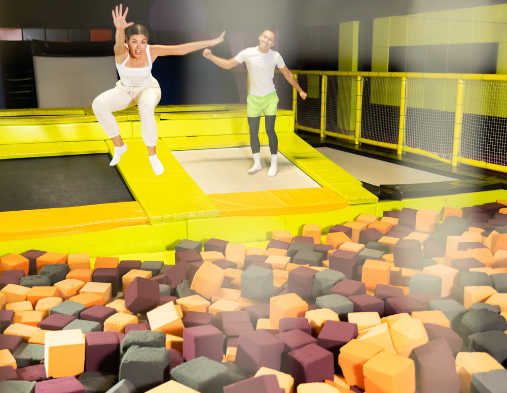 Joyful girl jumping into foam pit at indoor trampoline arena