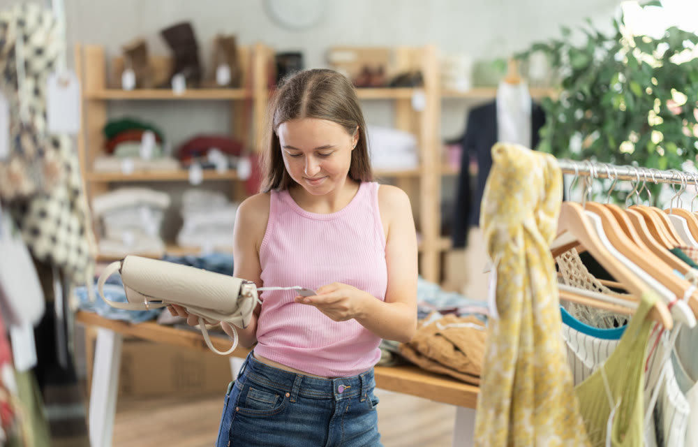 Young teen girl shopping - choosing a fashionable handbag in clothing store