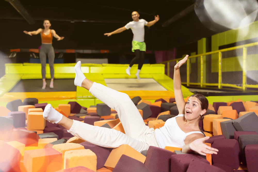 Happy girl diving into foam cube pit at indoor trampoline park
