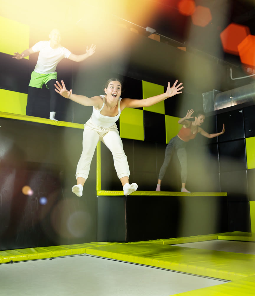 Girl acrobatic athlete jumping and exercising on trampoline indoors, modern hobby and fitness concept