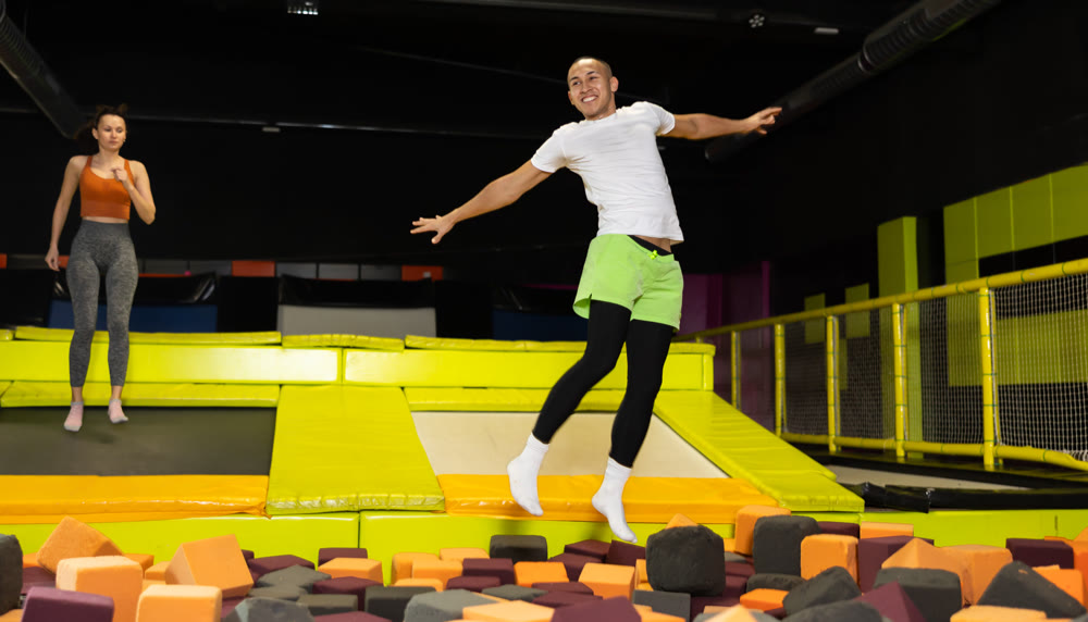 Joyful guy jumping into foam pit at indoor trampoline arena