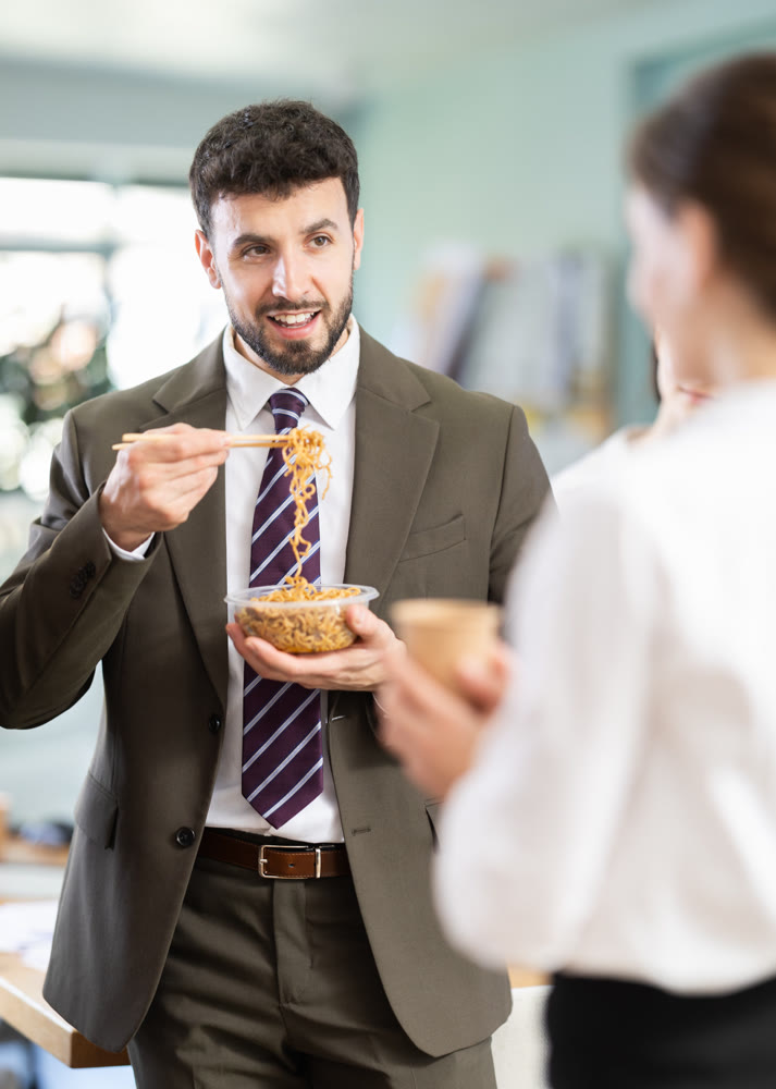 Male companys employees eat instant noodles, lunch time during break for staff