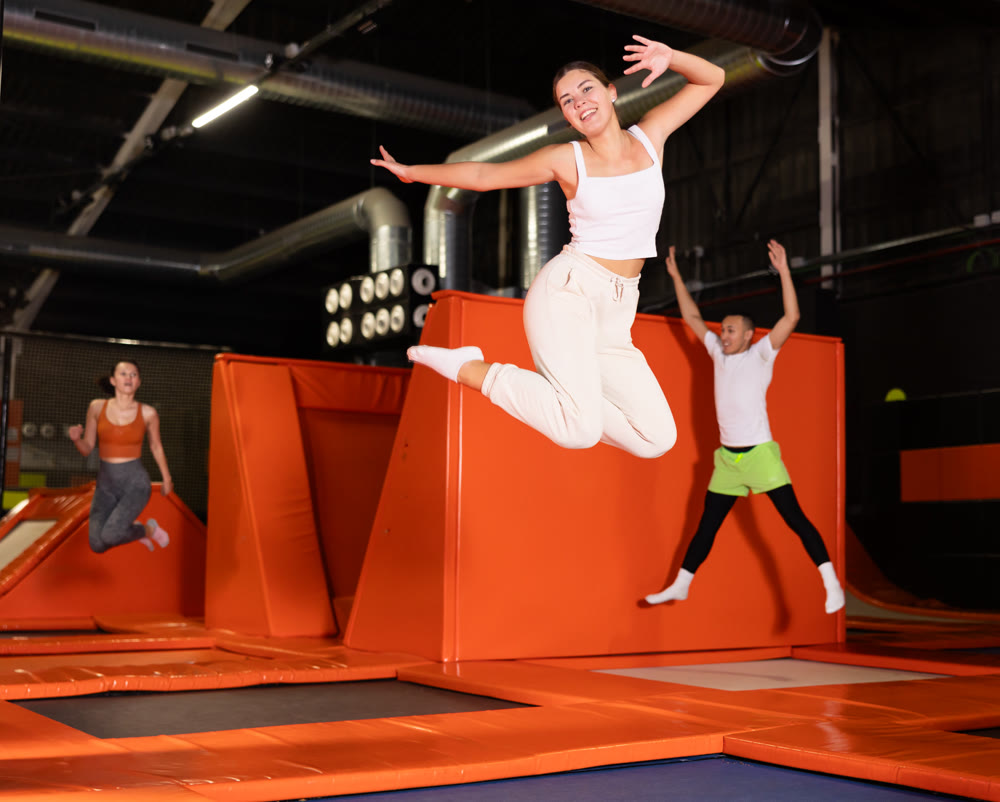 Girl acrobatic athlete jumping and exercising on trampoline indoors, modern hobby and fitness concept