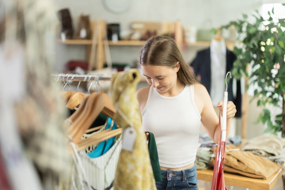 Girl chooses a set of clothes for summer. Visitor to the boutique examines the new summer collection of clothes